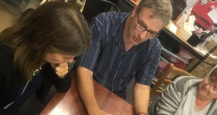 Three people sitting around a laptop having a discussion.
